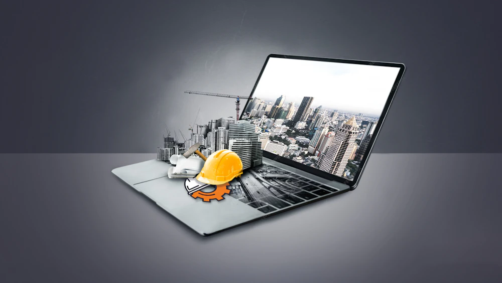 Laptop met een stedelijke skyline uit het scherm, naast een gele bouwhelm, blauwdrukken en gereedschap op het toetsenbord.