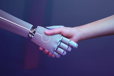Een menselijke hand en een geavanceerde metalen robothand geven elkaar een hand tegen een paars-blauwe achtergrond.De wereld is in de ban van kunstmatige intelligentie
